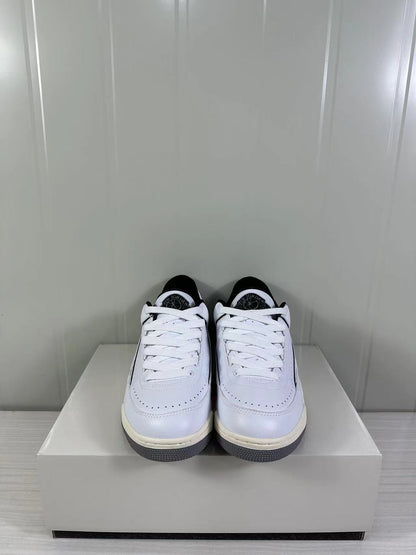 Front view of the white and black low-top sneakers with white laces and perforated toe panels.