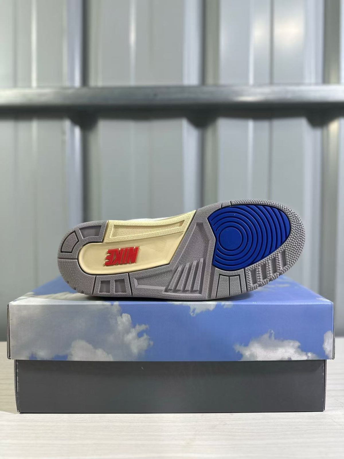 Outsole view showing gray rubber sections, a blue circular traction area, and red branding.