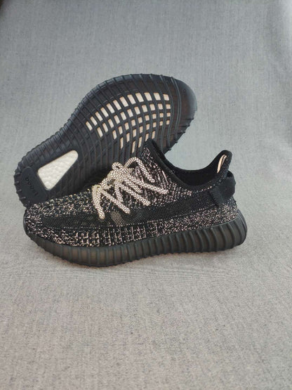 Pair of black 350 V2-style sneakers shown from the side and outsole, with light-colored laces and speckled detailing.
