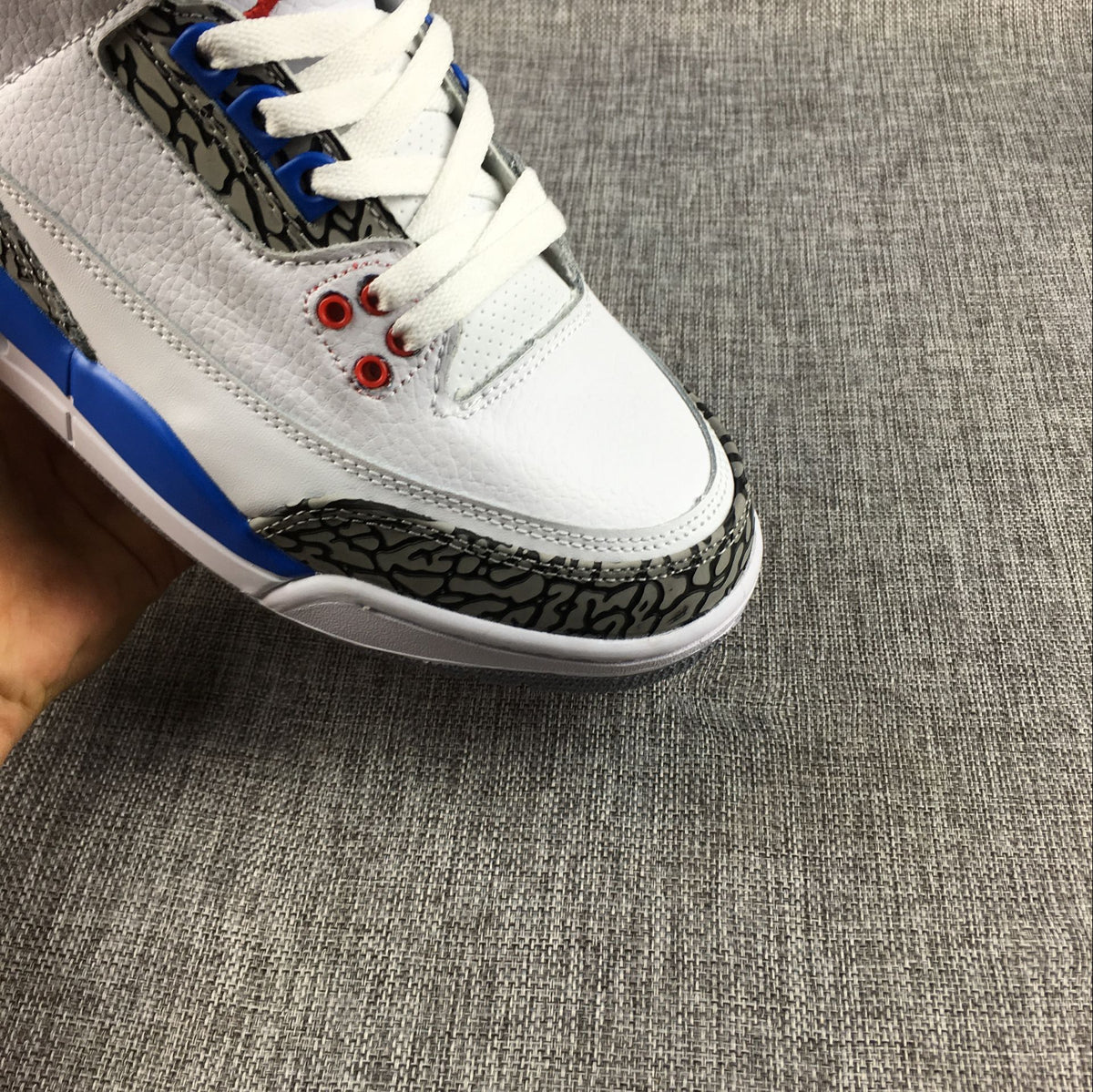 Close-up of the sneaker toe, white laces, red eyelets, and elephant-print overlay.