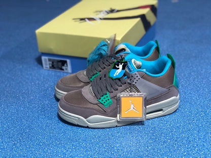 Pair of grey and teal Air Jordan 4 Retro SP sneakers displayed beside the shoe box and hangtags.
