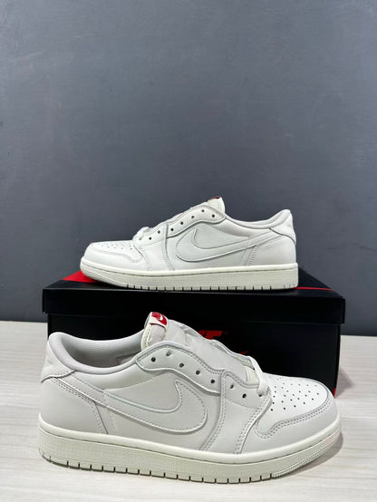 Close three-quarter view of a white low-top Jordan sneaker, showing the perforated toe box, side branding, laces, and layered construction.