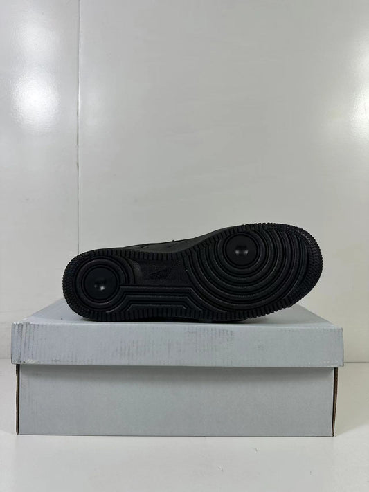 Black sneaker outsole showing circular traction grooves, photographed on a plain shoe box.