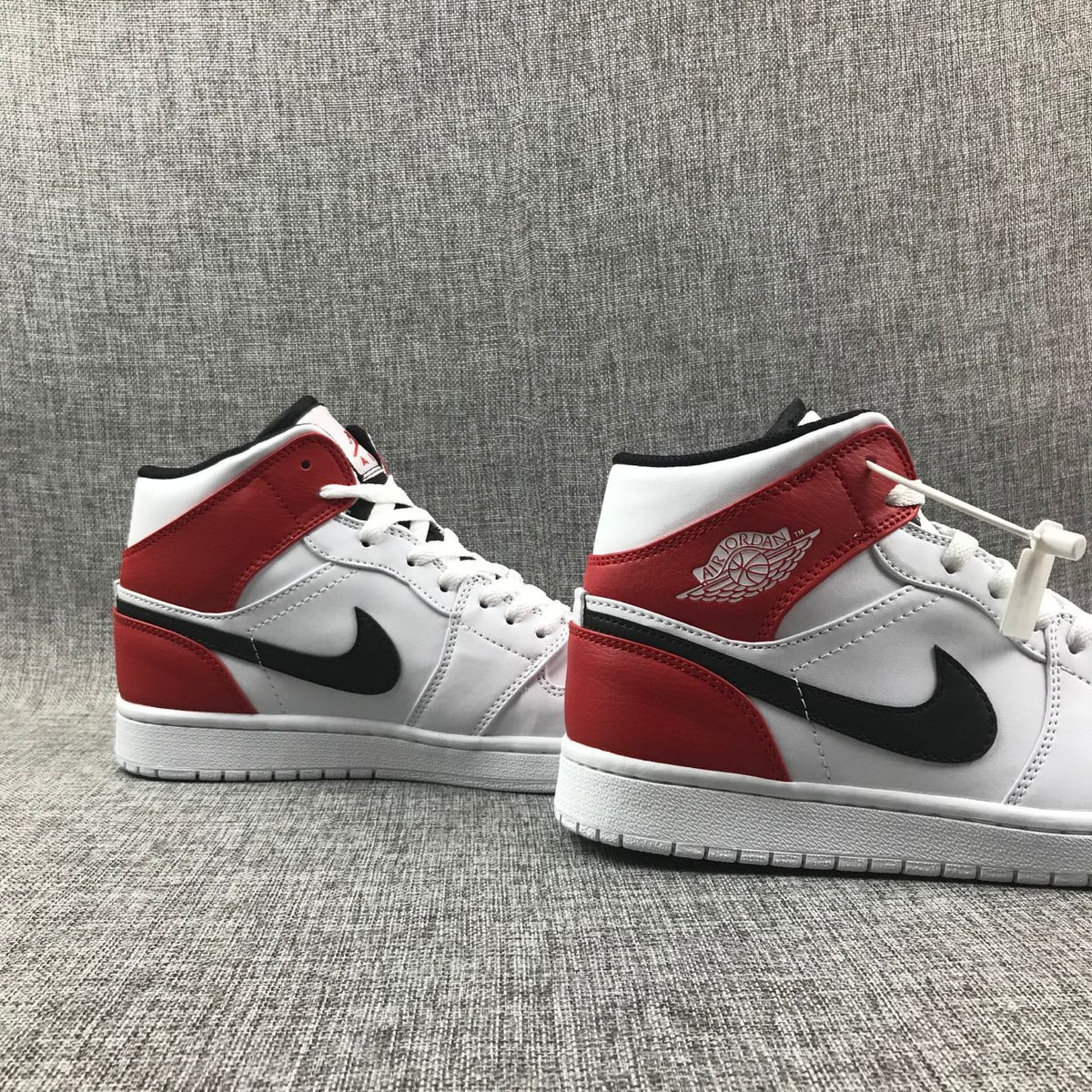 Pair of sneakers shown from the side, emphasizing the red ankle panels and white midsoles.