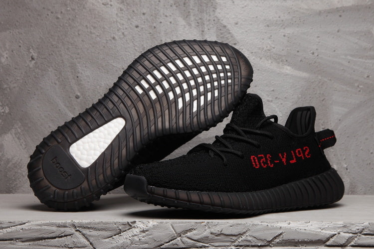 Pair of black 350 V2-style sneakers showing the ribbed outsole and red side lettering.