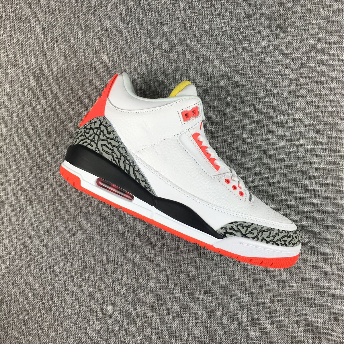 Angled side view of a white Jordan 3 sneaker with red accents and patterned overlays.