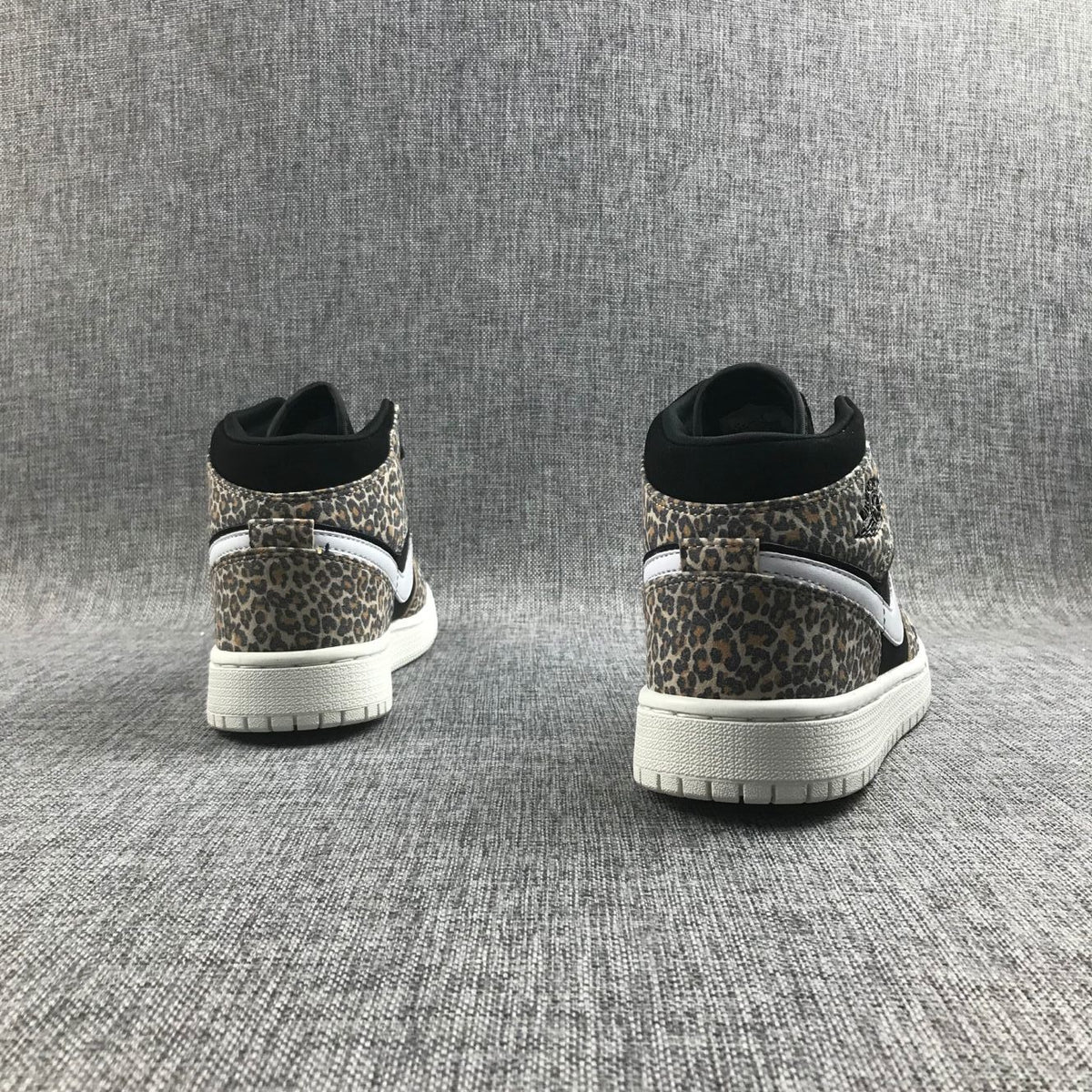 Rear view of the pair showing leopard-print heel panels, black collars, white Swoosh accents, and white outsoles.