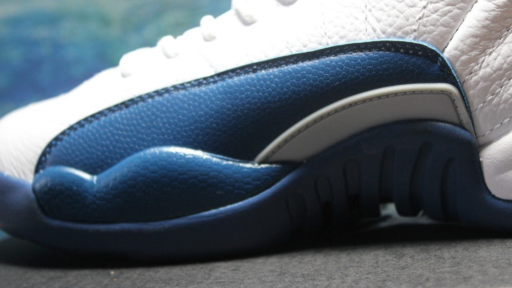 Close-up of the navy textured side overlay and outsole edge.