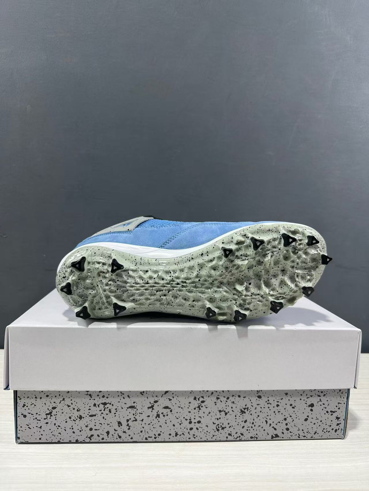 Bottom view of one sneaker showing the light speckled outsole and black traction studs.