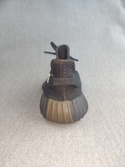 Rear view of a black sneaker showing the padded heel collar, pull tab, stitching, and ribbed outsole.