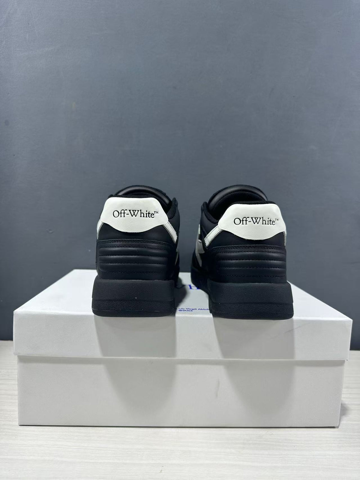 Rear view of the pair showing white branded heel panels and padded black heel sections.
