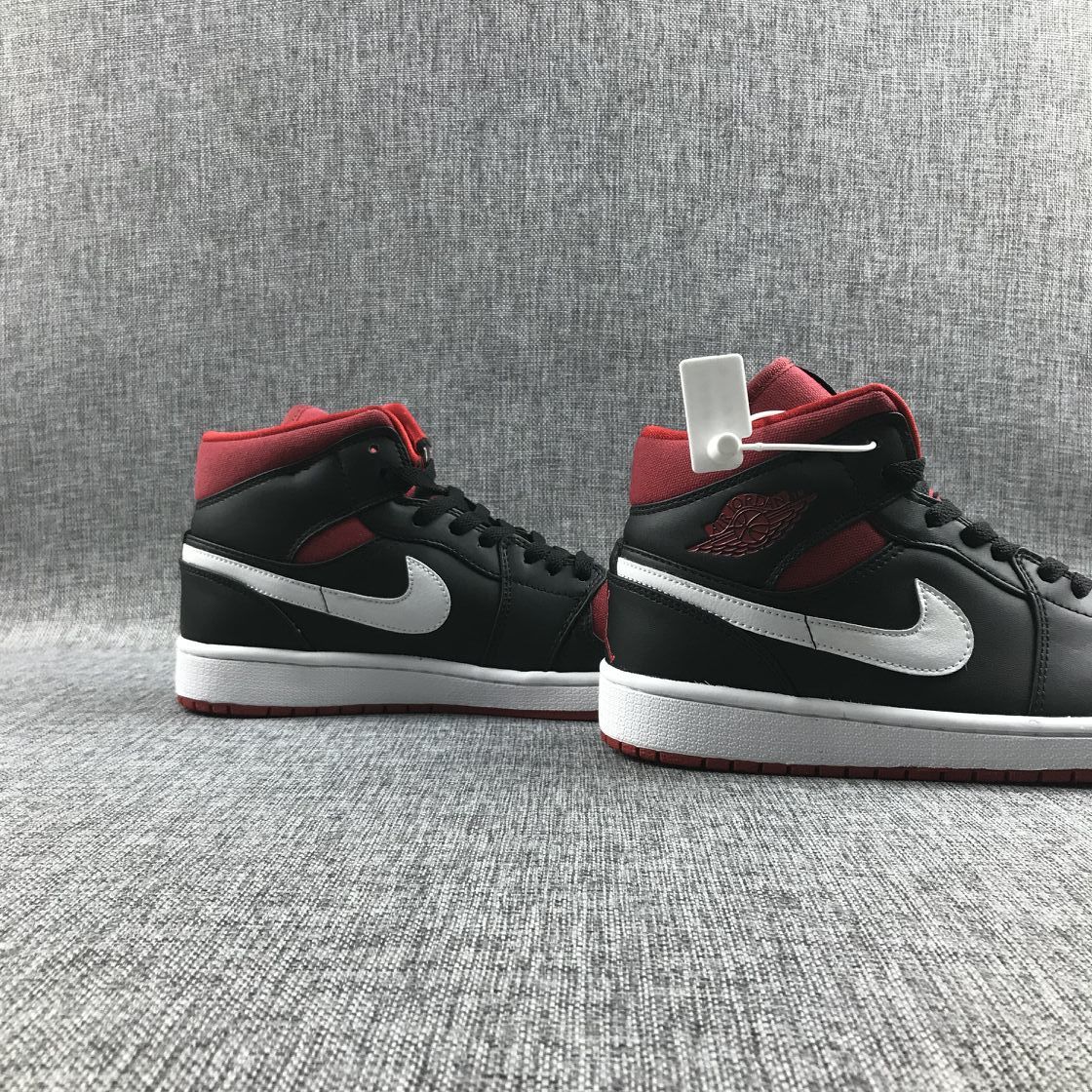 Three-quarter view of the pair showing the black and red upper, white Swooshes, and white midsoles.