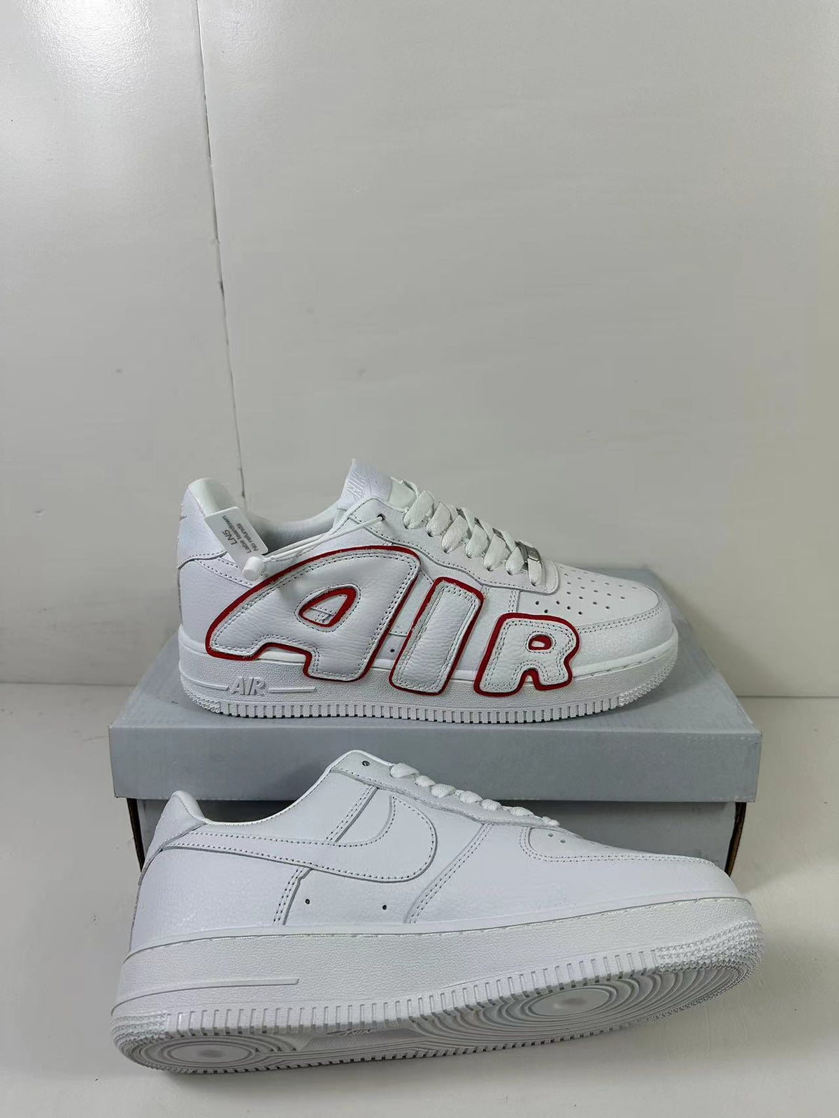 Angled product view showing one sneaker with AIR lettering alongside the mostly white lateral side of the other shoe.
