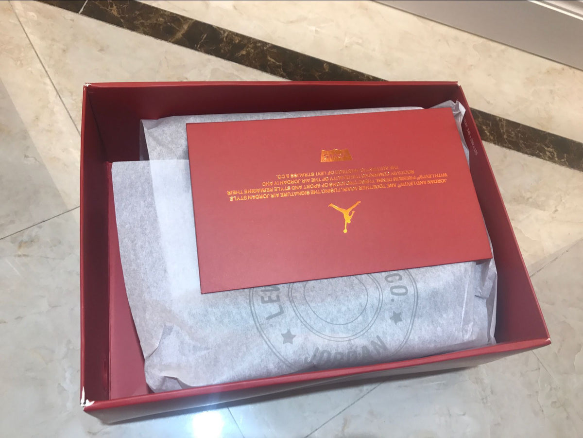 Open red shoe box containing tissue paper and a red printed insert.