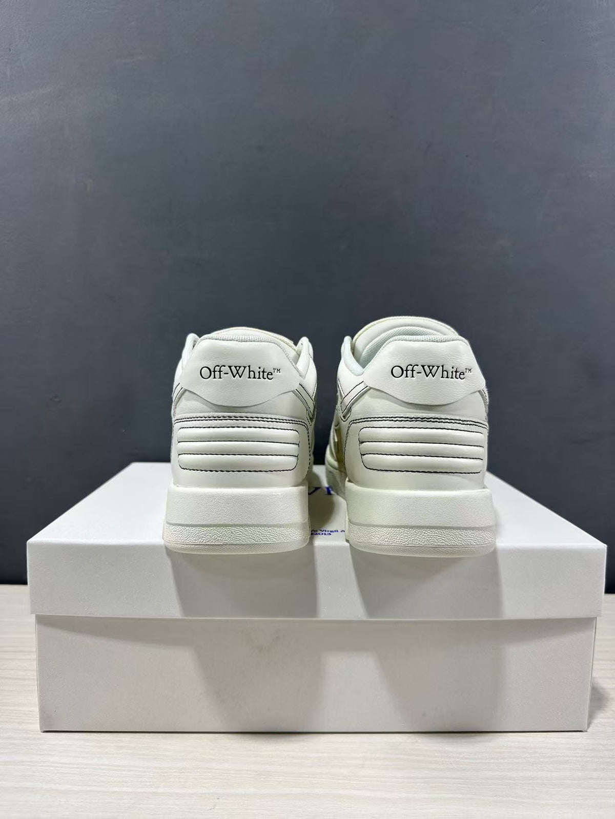Rear view of a pair of cream-white sneakers showing padded heel panels and Off-White branding.