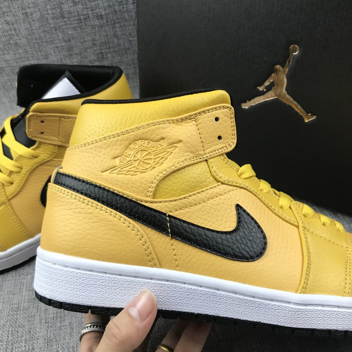 Close-up of the black Swoosh and embossed winged basketball emblem on the yellow ankle panel.