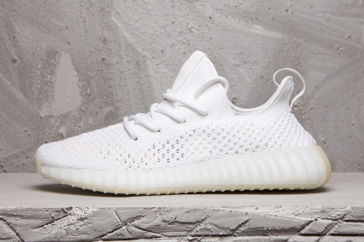 Side profile of a white sneaker showing the textured upper, heel pull tab, and ribbed sole unit.