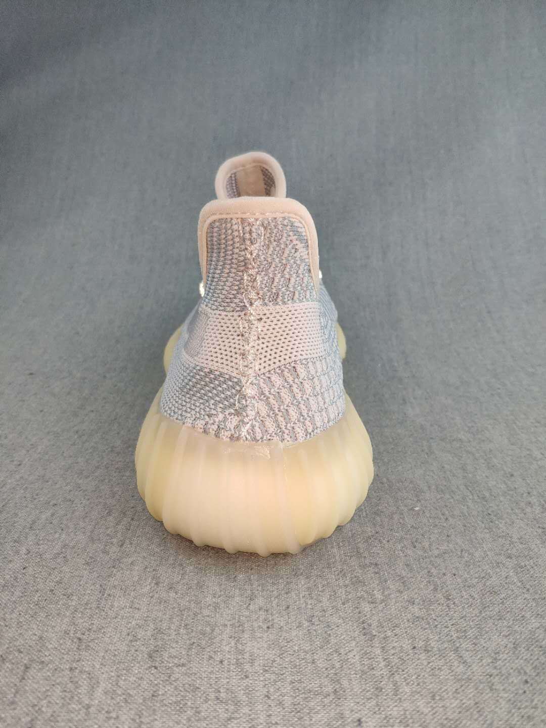 Rear view of a Yeezy 350 V2 style sneaker showing the knit heel, pull tab, and translucent gum-colored sole.