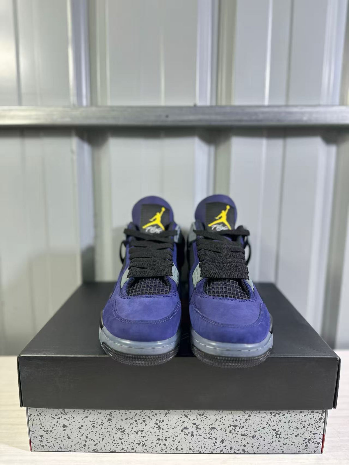 Front view of a pair of purple Jordan Air Jordan 4 sneakers with black laces and yellow tongue logos.