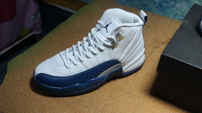 Three-quarter view of one white and navy high-top sneaker beside its box.