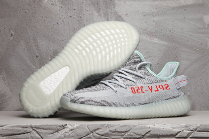 Pair of gray and white Yeezy 350 V2 sneakers showing the patterned upper and translucent ribbed outsoles.