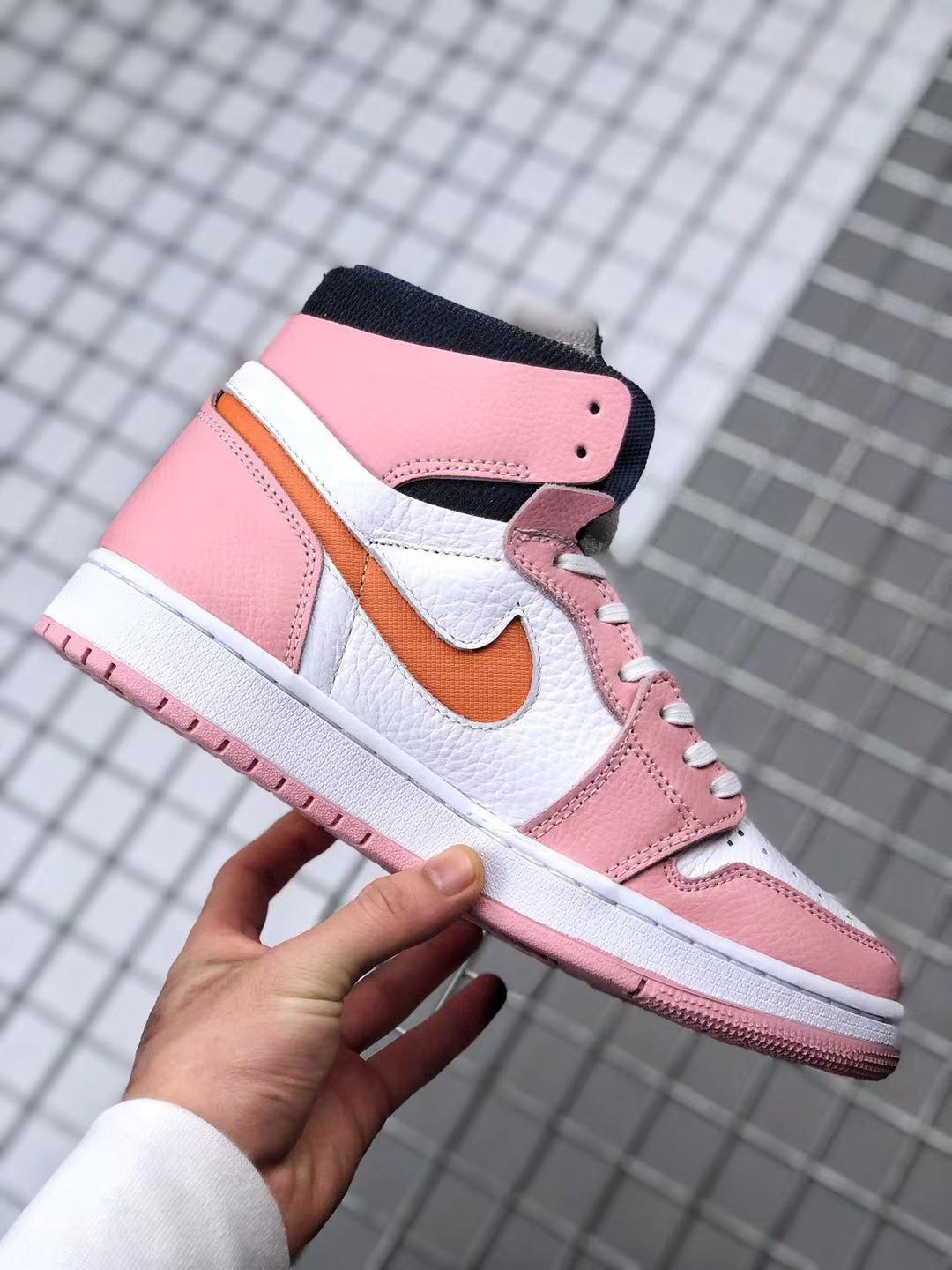 Side view highlighting the pink overlays, white mid-panel, orange side accent, and white midsole.