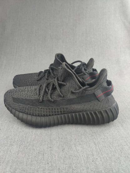 Black knit sneakers shown from a front-side angle with red heel stitching.