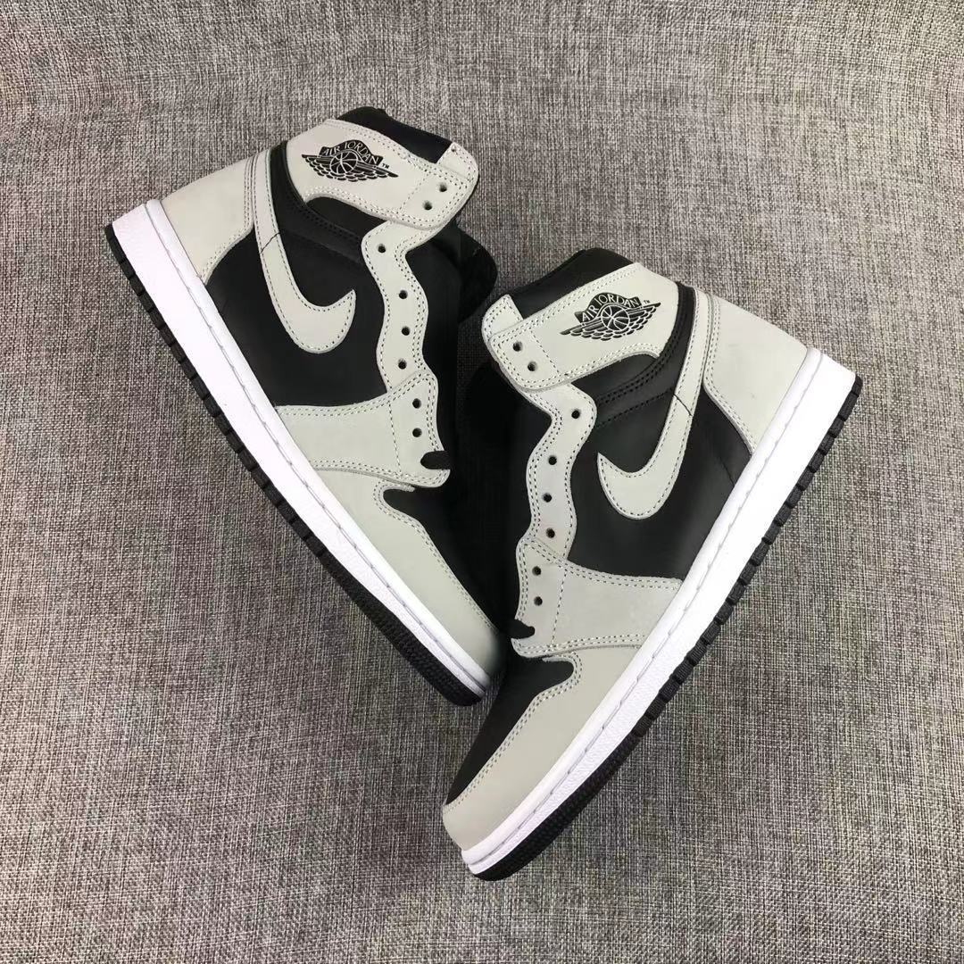 Pair of black and grey sneakers arranged diagonally on a textured surface.