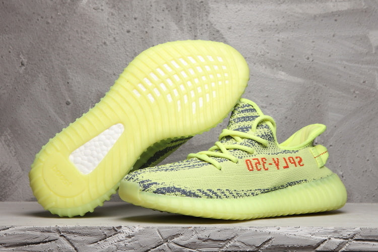 Pair of lime green Yeezy 350 V2-style knit sneakers shown from the side and outsole.
