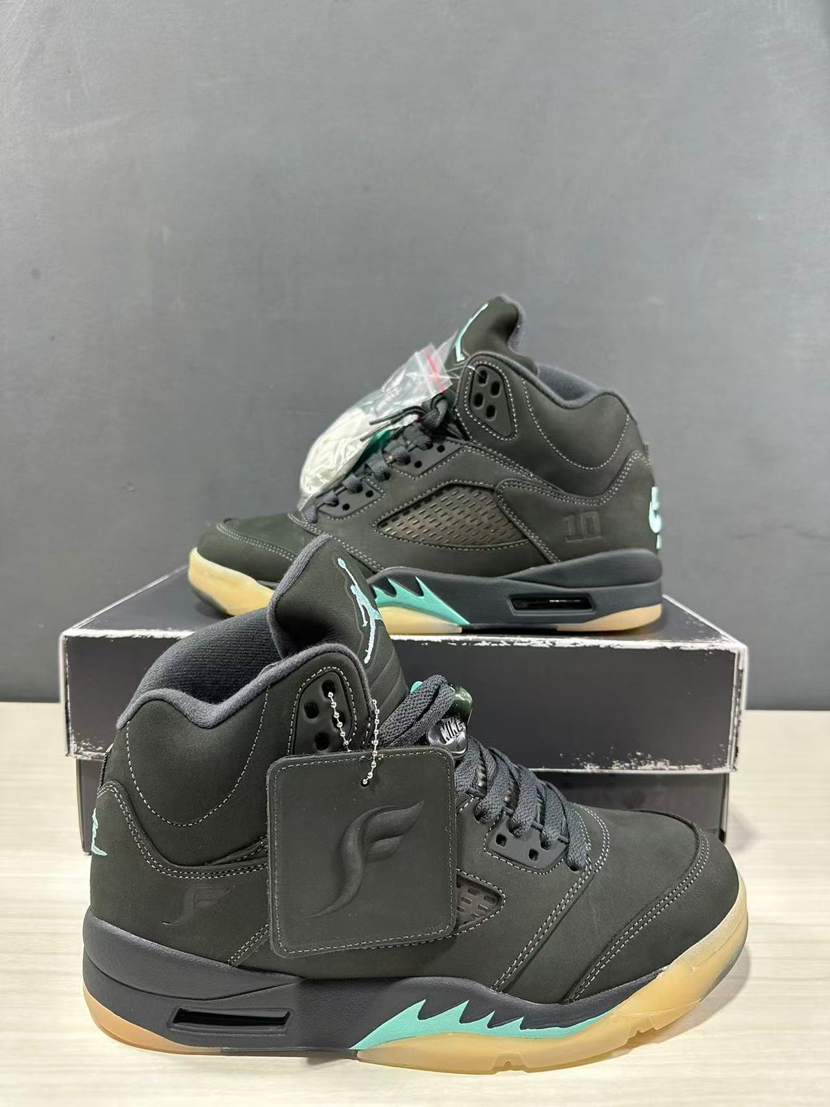 Close angled view of the Jordan Air Jordan 5 pair showing the padded collars, lace areas, hangtags, and aqua midsole details.