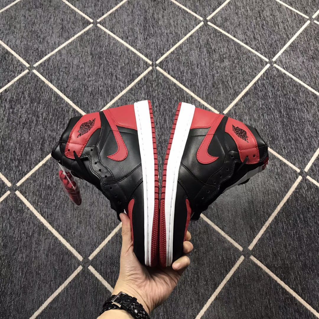 Two black and red high-top sneakers displayed side by side, showing the white midsoles and red outsoles.
