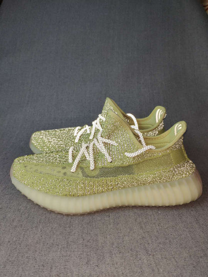 Pair of green low-top sneakers shown from a side angle with white laces and translucent ribbed soles.