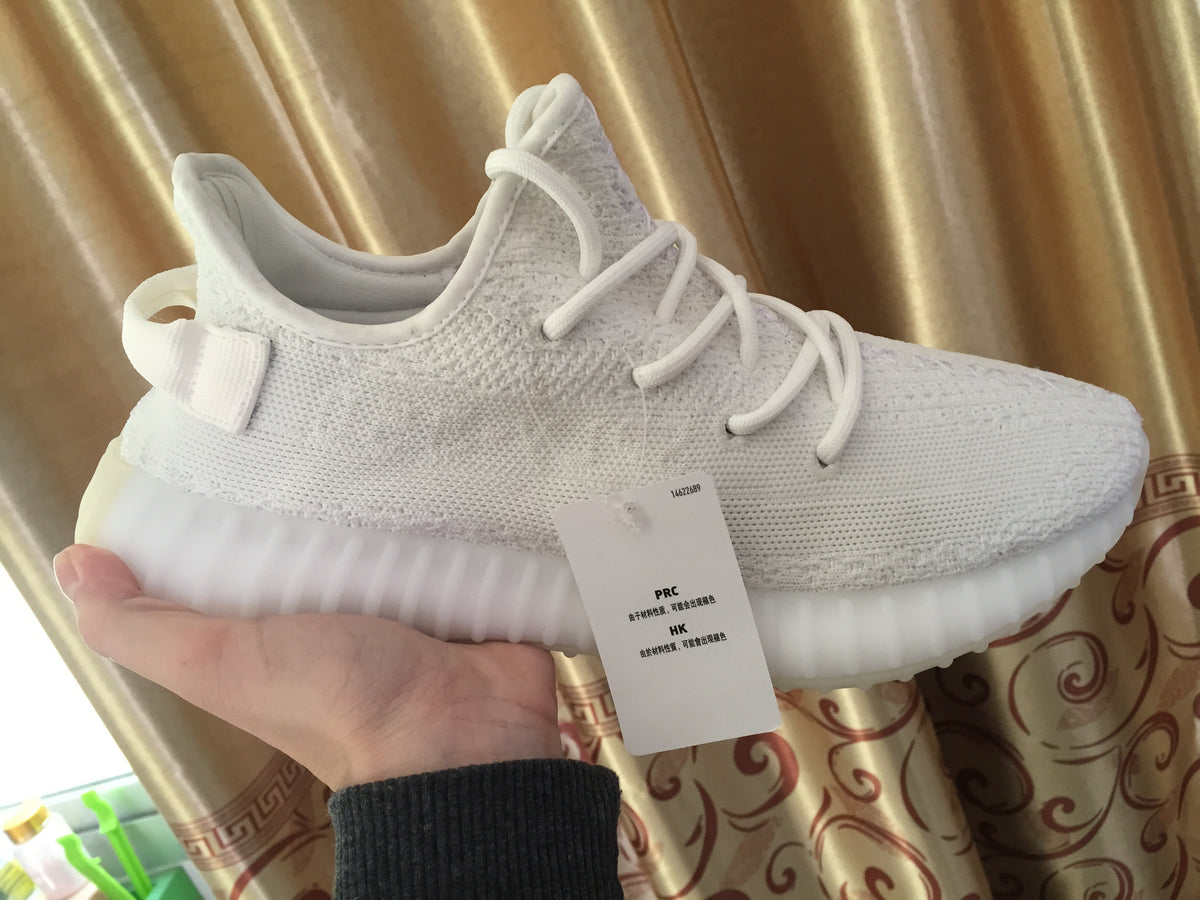 Side profile of the white sneaker showing the knitted upper, laces, heel tab, and ribbed sole.