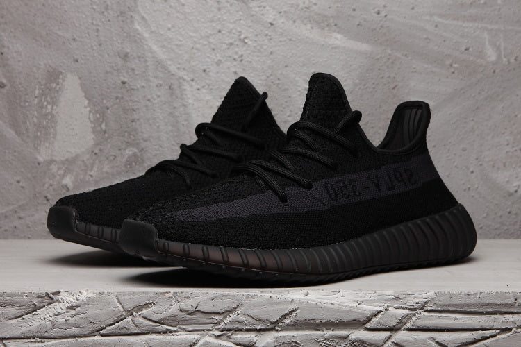 Pair of black Yeezy 350 V2 sneakers in a three-quarter front view.