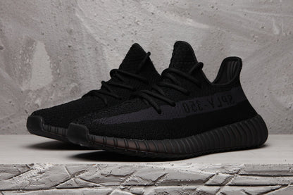 Pair of black Yeezy 350 V2 sneakers in a three-quarter front view.