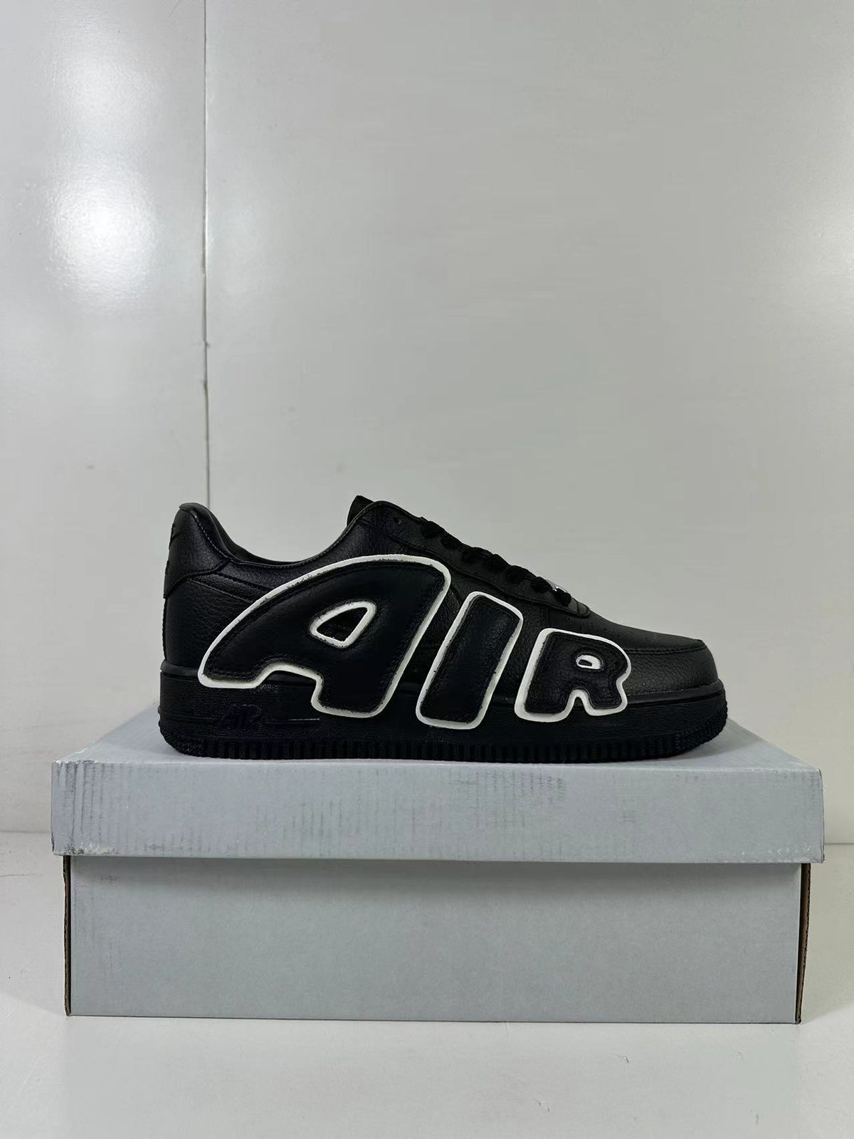 Side view of a black low-top sneaker featuring oversized outlined AIR lettering.