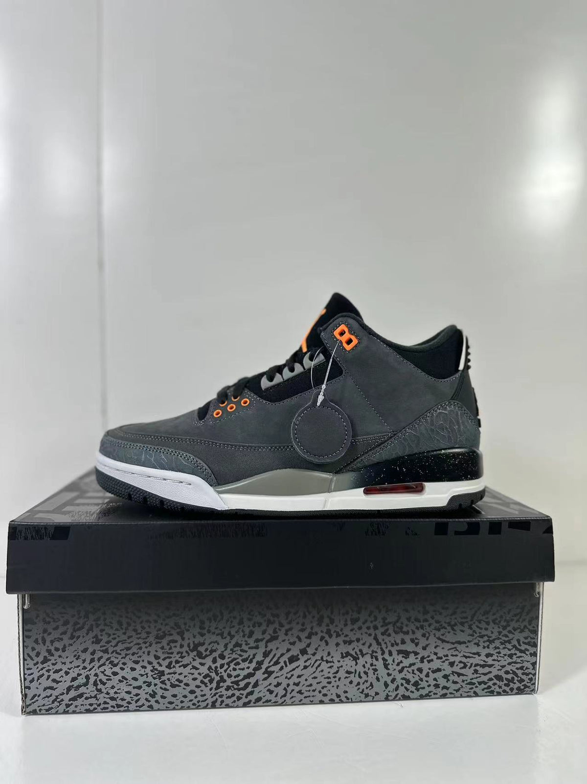 Side profile showing the dark gray upper, elephant-print overlays, speckled black midsole, visible red-tinted sole detail, and white outsole edge.