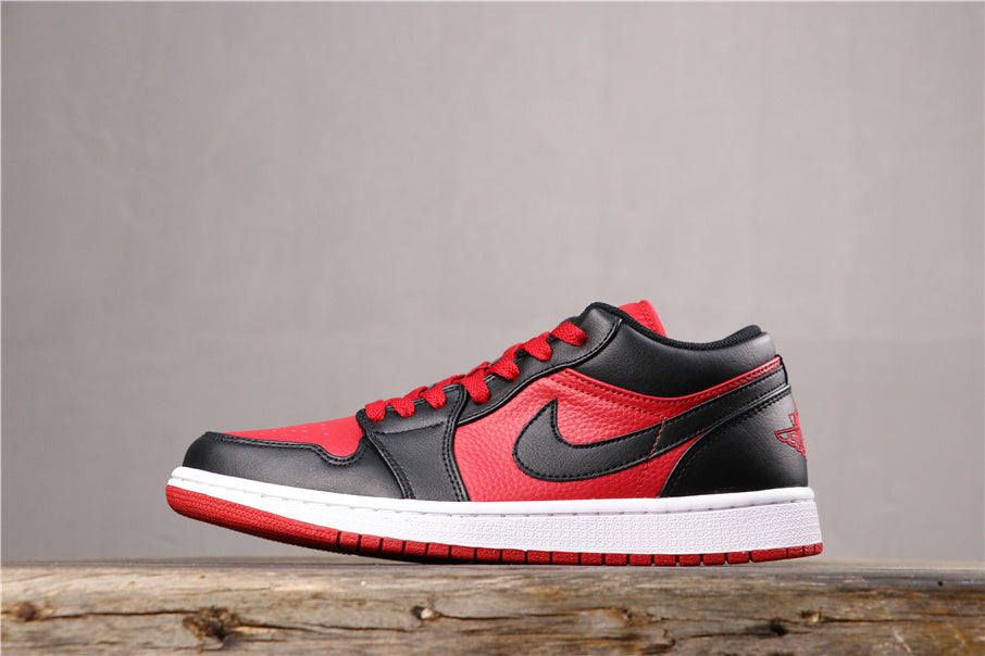 Side view of black, red, and white Jordan low-top sneakers with red laces, contrasting Swoosh branding, a white midsole, and red outsole.