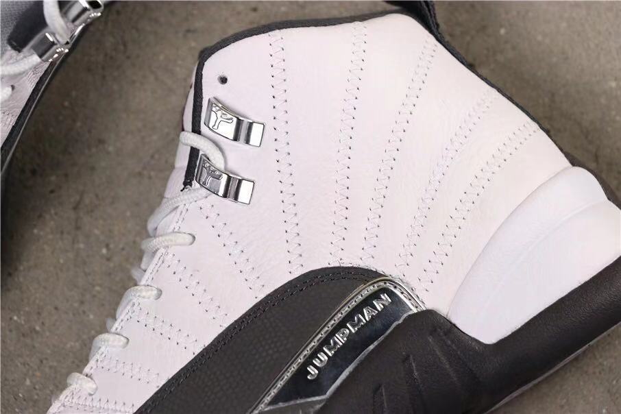 Side close-up showing the white upper, dark grey overlay, metal lace hardware and Jordan side detail.