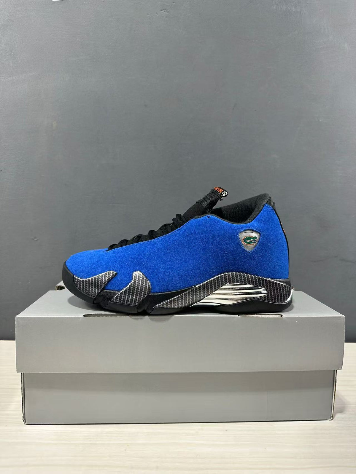 Side profile of a blue Jordan Air Jordan 14 Retro sneaker with black trim, silver accents, and a Florida Gators emblem.
