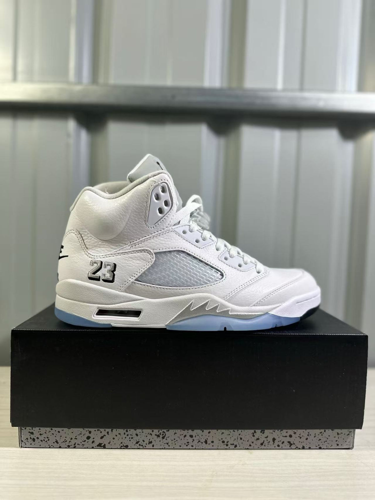 Single white and silver high-top sneaker displayed in side profile on a black box.