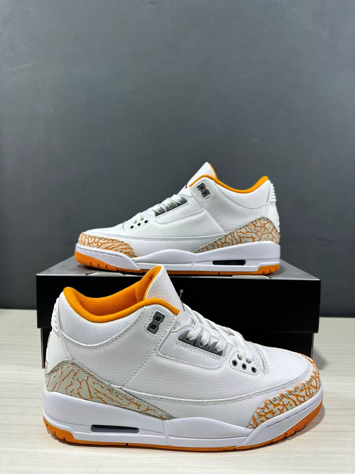 Angled side view showing the white mid-top upper, orange collar lining, elephant-print overlays and visible heel Air unit.