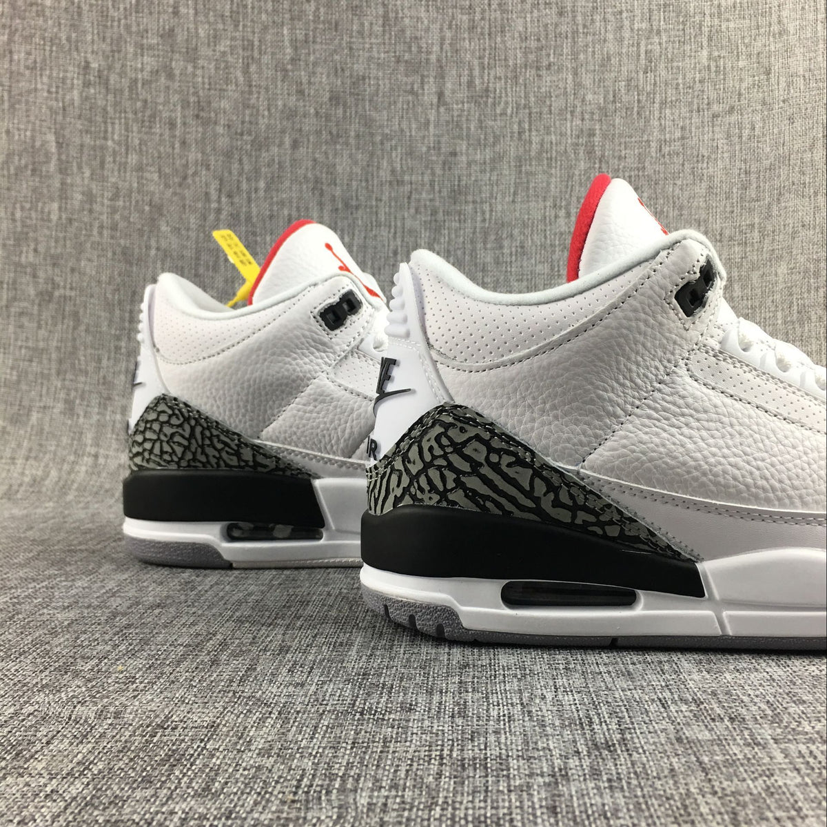 Pair of white Jordan 3 sneakers shown from the heel side with elephant-print panels