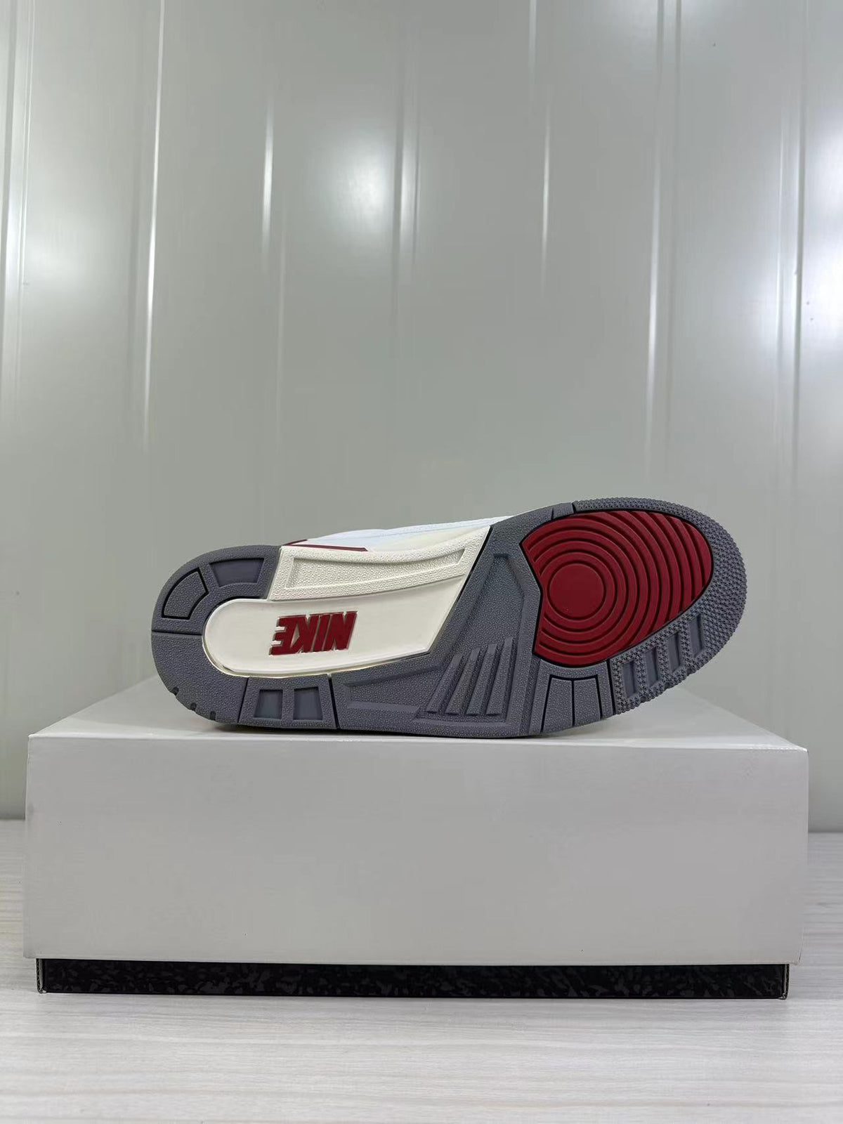 Outsole view showing gray tread sections, a red circular traction area, and visible branding.