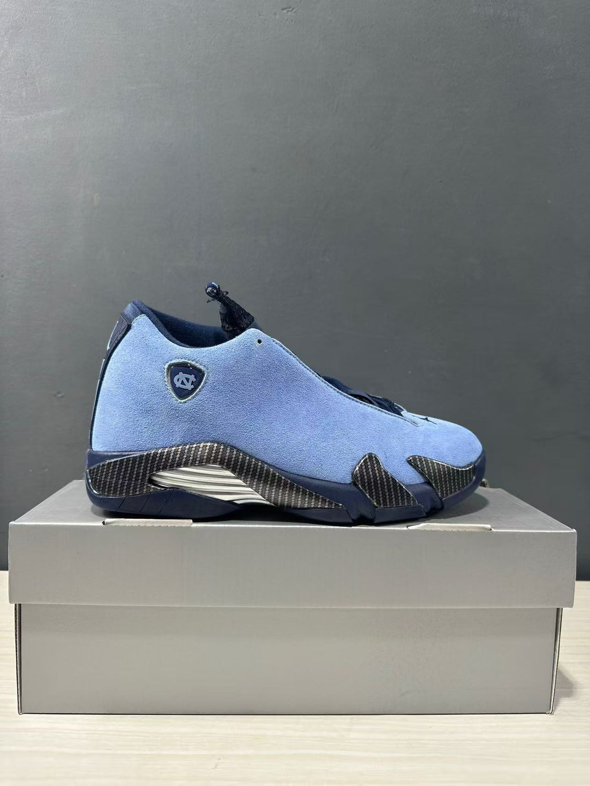 Side profile of a blue Jordan Air Jordan 14 sneaker displayed on a box.