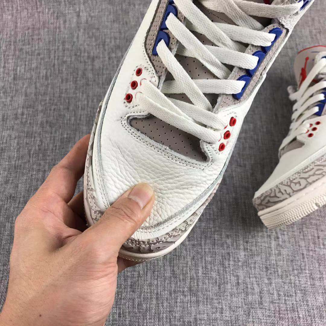Close-up of the white textured toe box, grey perforated tongue area, white laces, and red eyelets.
