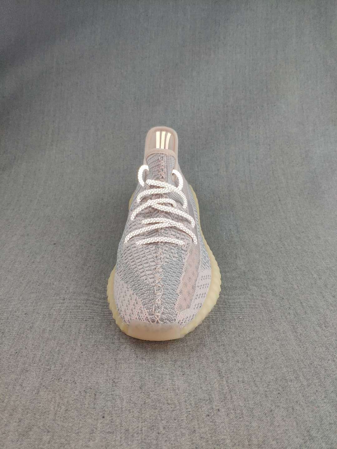Front view of a Yeezy 350 V2 style sneaker showing the rounded toe, knit upper, and white laces.