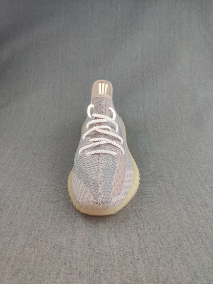 Front view of a Yeezy 350 V2 style sneaker showing the rounded toe, knit upper, and white laces.
