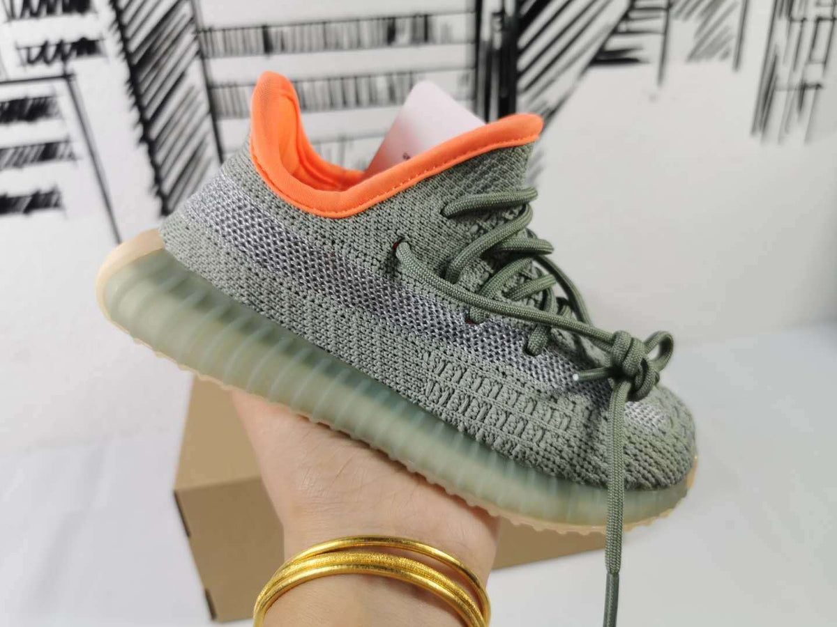 Side profile of the gray and orange sneaker held above a cardboard shoebox.