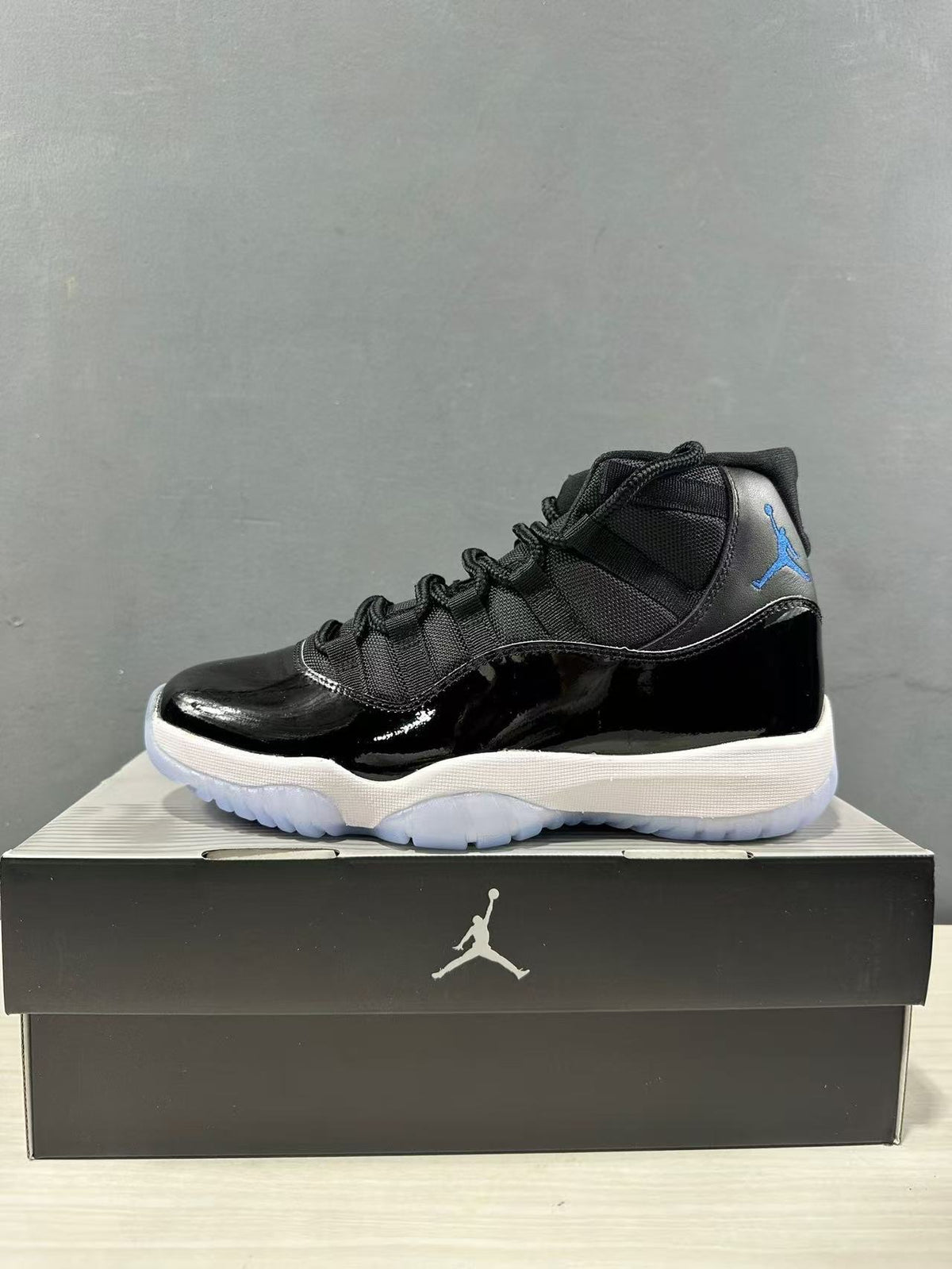 Side profile of a black and blue high-top sneaker with blue Jumpman branding and a white midsole on a shoebox.